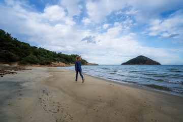 Rear view of a little girl running along an empty sandy beach on Thassos Island in late autumn