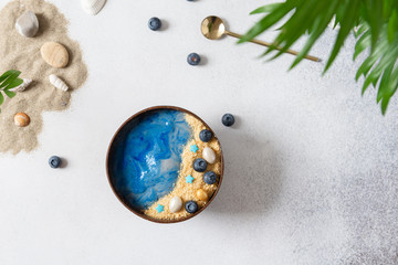 Summer dessert. Smoothie bowl with blue spirulina topped like a beach with sea and sand. Detox,...