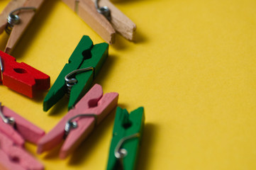 Multicolored decorative wooden clothespins on a yellow ocher background, macro closeup, copy space