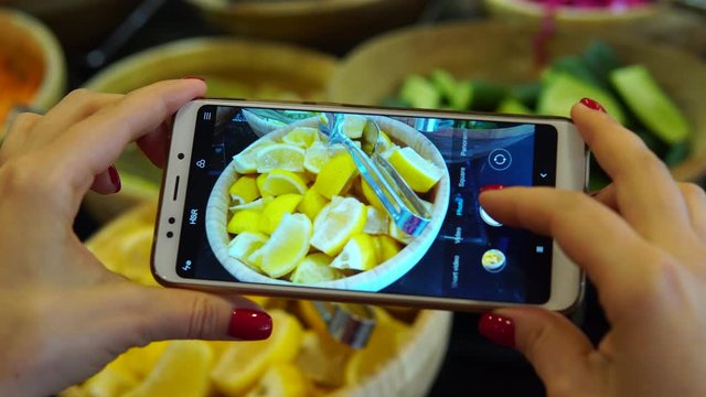 A woman is photographing a plate of salads in a buffet restaurant. Social network blogger concept photo. Healthy and tasty food.