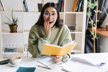 Surprised optimistic young girl student indoors studying.