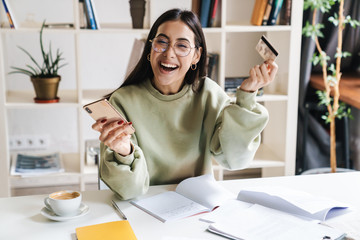 Happy optimistic young girl student holding credit card.