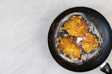 Frying grated potatoes pancakes in the frying pan