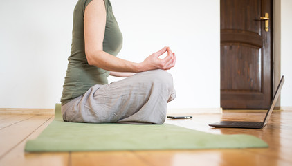 woman with laptop doing yoga at home coronavirus