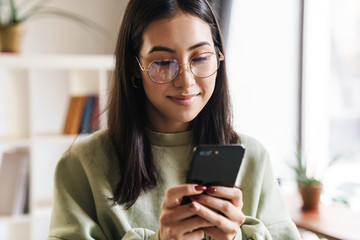 Concentrated young girl student using mobile phone.