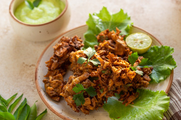 Indian cuisine Indian food. pakora traditional Indian deep-fried snack. pakoras on black plate with coconut chutney sauce curry leaves. national appetiser authentic vegetarian Asian food. travel food