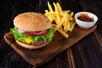 Burger with french fries on a wooden background. Beef burger with fresh lettuce, tomato and cheese.