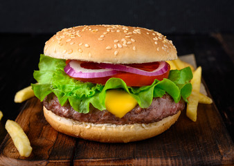 Burger with french fries on a wooden background. Beef burger with fresh lettuce, tomato and cheese.