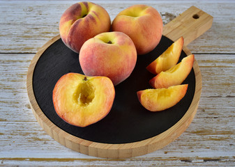 Naklejka na ściany i meble Ripe juicy peaches with velvet sides on a wooden cutting board