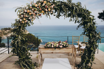 Wedding decorations. The ceremony area in the villa by the pool overlooking the sea is decorated with flower arrangements, golden vases and candles