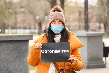 Young Asian woman wearing protective mask on city street. Concept of Coronavirus epidemic