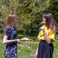 Young girls have fun time in the park.  The sisters communicate and share secrets. Happy sisters are enjoying a warm spring day