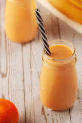 Tangerine and banana smoothie on wooden table