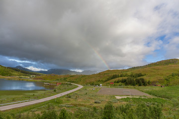 Fototapeta premium road to Unstad under colorful Rainbow in Lofoten islands, Norway, selective focus