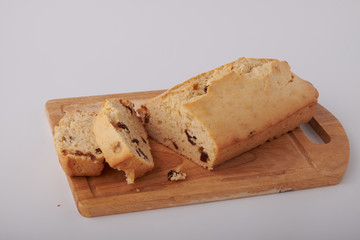 Checkered napkin, pieces of muffin with raisin on plastic cutting board on wooden table