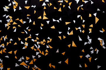 Golden silver confetti isolated on black background.