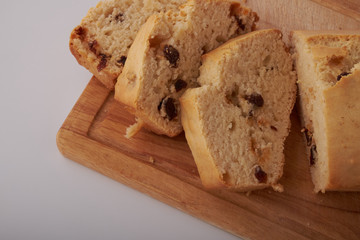 Checkered napkin, pieces of muffin with raisin on plastic cutting board on wooden table