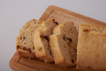 Checkered napkin, pieces of muffin with raisin on plastic cutting board on wooden table