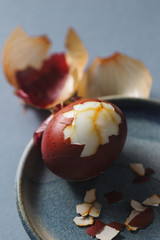 Close up of half-peeled egg colored with natural dye - onion skins