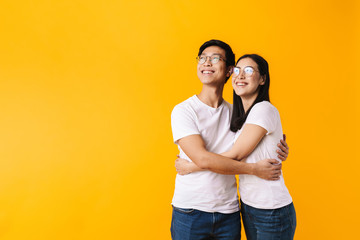 Image of cheerful multinational man and woman hugging and looking upward