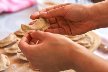 cooking healthy food at home. closeup woman hands preparing dumplings from rye flour over wooden cutting board