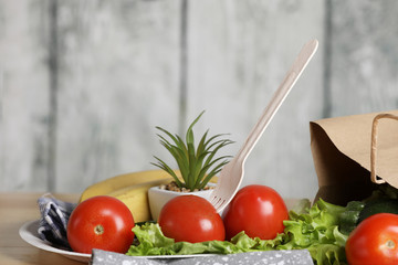 ingredients for cooking. Fresh vegetables on a wooden table. Tomato and salad. Ecology products. Recycle paper bag. Wooden recycle fork