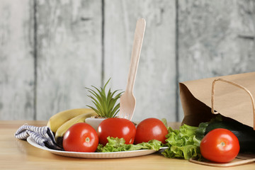 ingredients for cooking. Fresh vegetables on a wooden table. Tomato and salad. Ecology products. Recycle paper bag. Wooden recycle fork