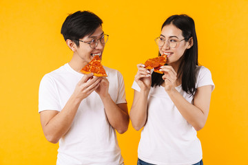 Image of cheerful multinational couple smiling and eating pizza