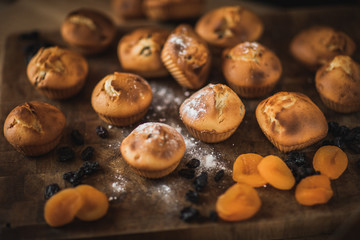 Freshly baked muffins with raisins and dried apricots, shot on a dark background. Background for baking and cooking.