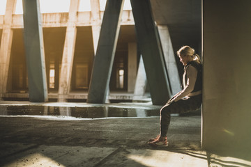 Young Caucasian woman taking a exercises break, leaning on the wall 