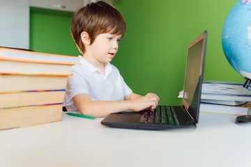Boy studying at home with notebook and doing school homework. Distance learning online education.