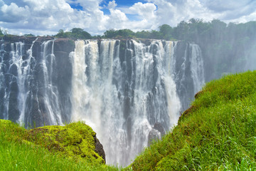 Panorama view to the dramatic waterfall and clouds at Victoria Falls on the Zambezi River,...