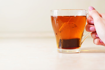 Cup of tea in hand on a light blurred background