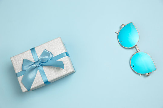 Gift, present box and eyeglasses. Monochrome stylish and trendy composition in blue color on studio background. Top view, flat lay. Pure beauty of usual things around. Copyspace for ad. Weekend