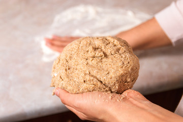 process of baking health bread at home. closeup woman hands kneading dough from rye flour on marble countertop in bright kitchen