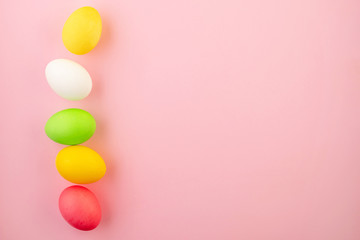Beautiful easter eggs painted in yellow, red and green pastel colors on a pink background.