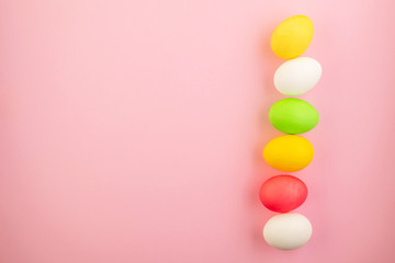 Beautiful easter eggs painted in yellow, red and green pastel colors on a pink background.