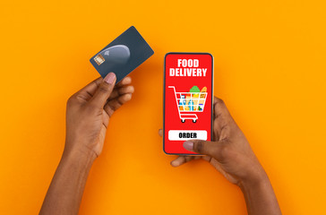 Female hands holding credit card and smartphone with food delivery app