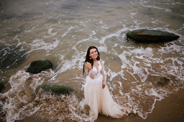 Romantic beautiful bride in white dress posing on terrace with sea and mountains in background