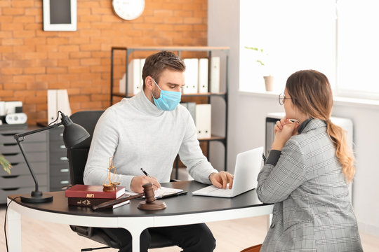 Male Lawyer In Protective Mask Working With Client In Office