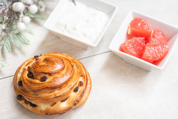 Healthy breakfast, cake with raisins, grapefruit and sour cream in white bowls on a wooden background.