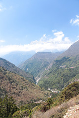 Fototapeta premium Beautiful mountain valley with flowing river in Himalayas in the day. Kongde Ri mountain in the background. Mountainside is covered by forest. Beautiful landscape. Theme of travel in Nepal.