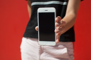 Close up on holding mobile smart phone over red background. Working remotely with information, modern communication lifestyle mock up display.