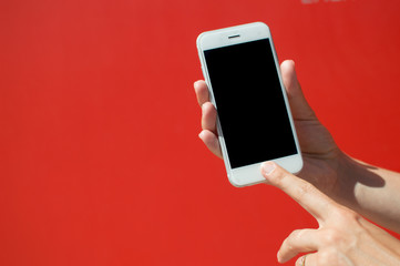 Close up on holding mobile smart phone over red background. Working remotely with information, modern communication lifestyle mock up display.