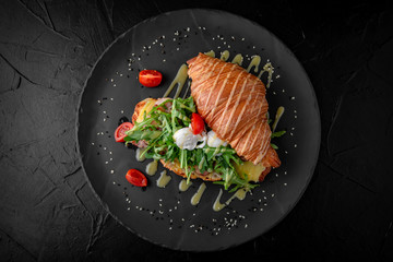 Delicious nutritious sandwich. Croissant with ham, egg, cheese and avocado and arugula. Perfect breakfast.