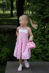 girl in a pink sundress stands on a stone and poses