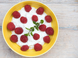 
Homemade cottage cheese with sour cream and raspberries, in a ceramic plate. Recipe for vegetarians.