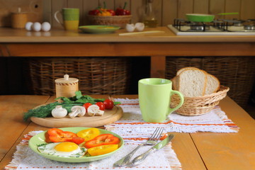Fried eggs and fresh vegetables on the wooden table in kitchen.