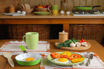 Fried eggs and fresh vegetables on the wooden table in kitchen.
