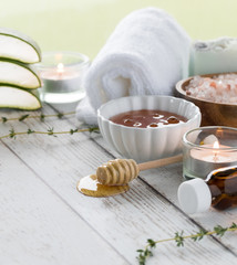 A close up of various natural remedies used is holistic therapy including honey, aloe and herbs.